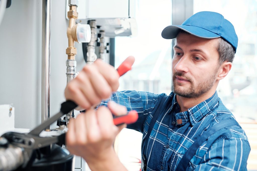 contemporary young mechanic from household maintenance service repairing pipe