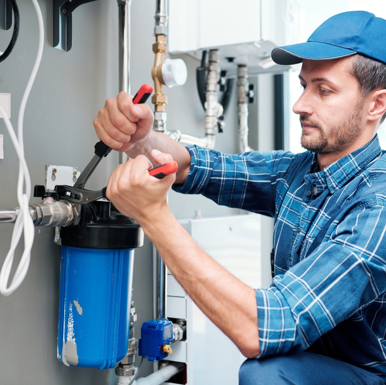 young plumber or technician installing or repairing system of water filtration e1671012139728